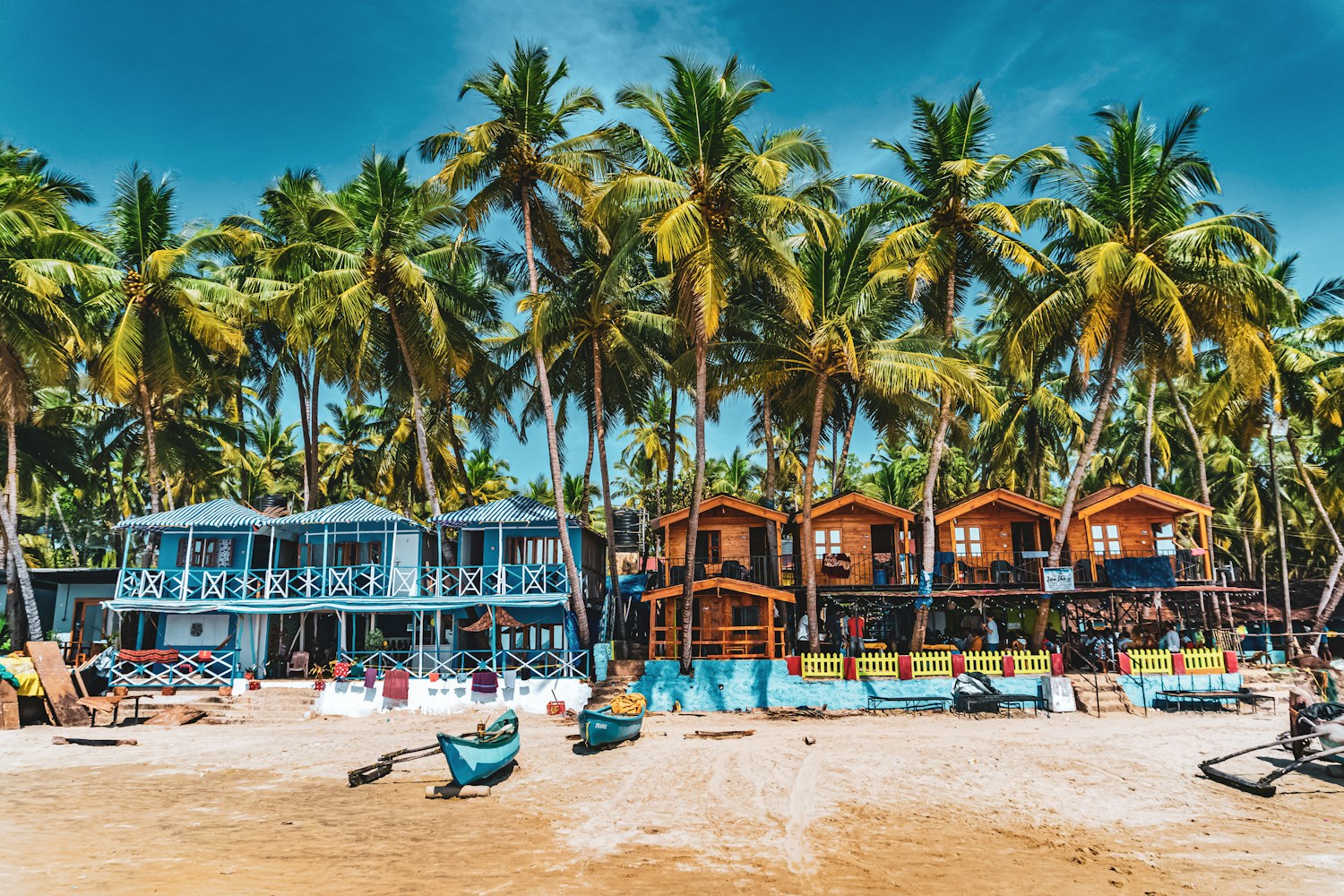 Colourful beach huts, fishing boats and coconut palms on Palolem Beach in South Goa