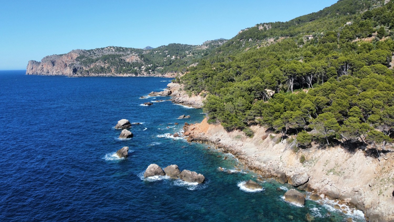 Pine-covered cliffs and blue Mediterranean water near Deià in Mallorca, Spain