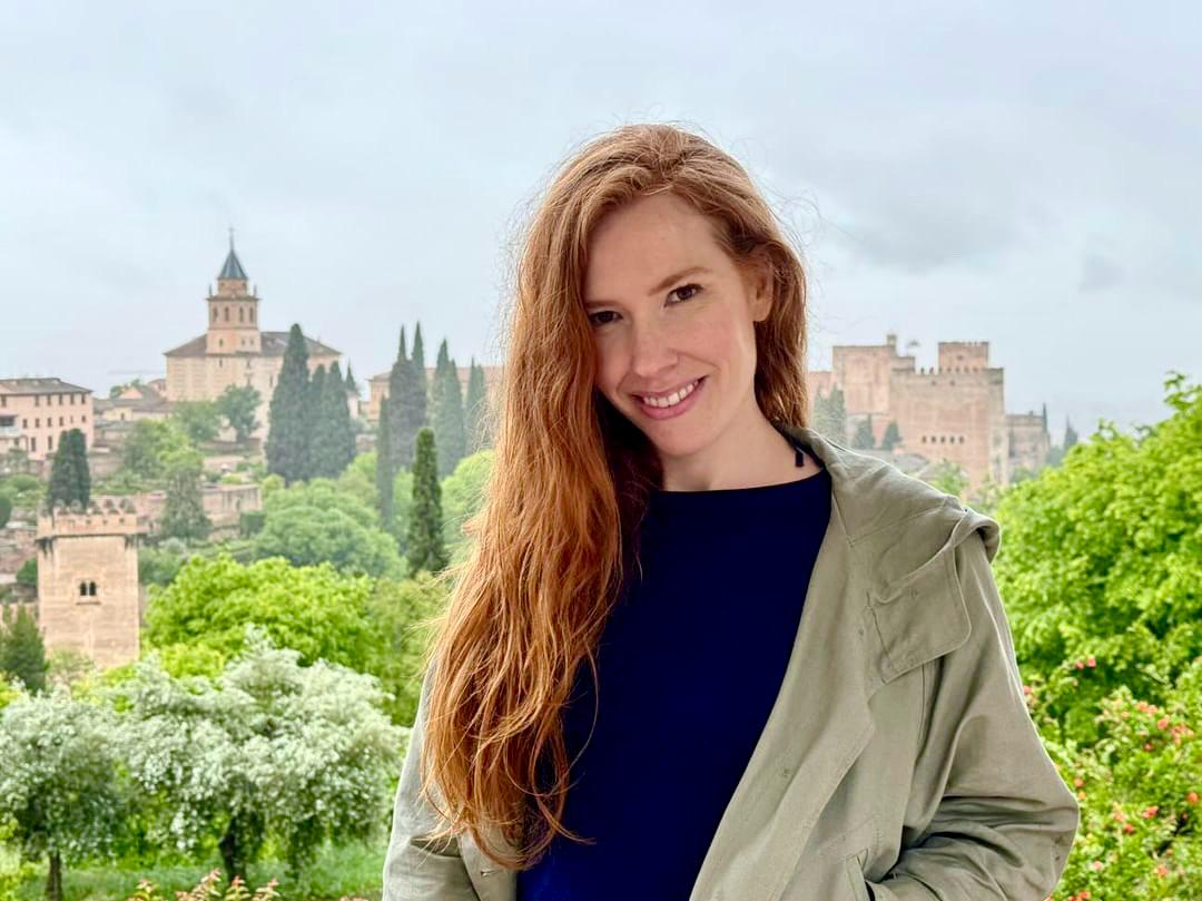 Megan Murphy, yoga business consultant, smiling with Granada’s Alhambra in the background